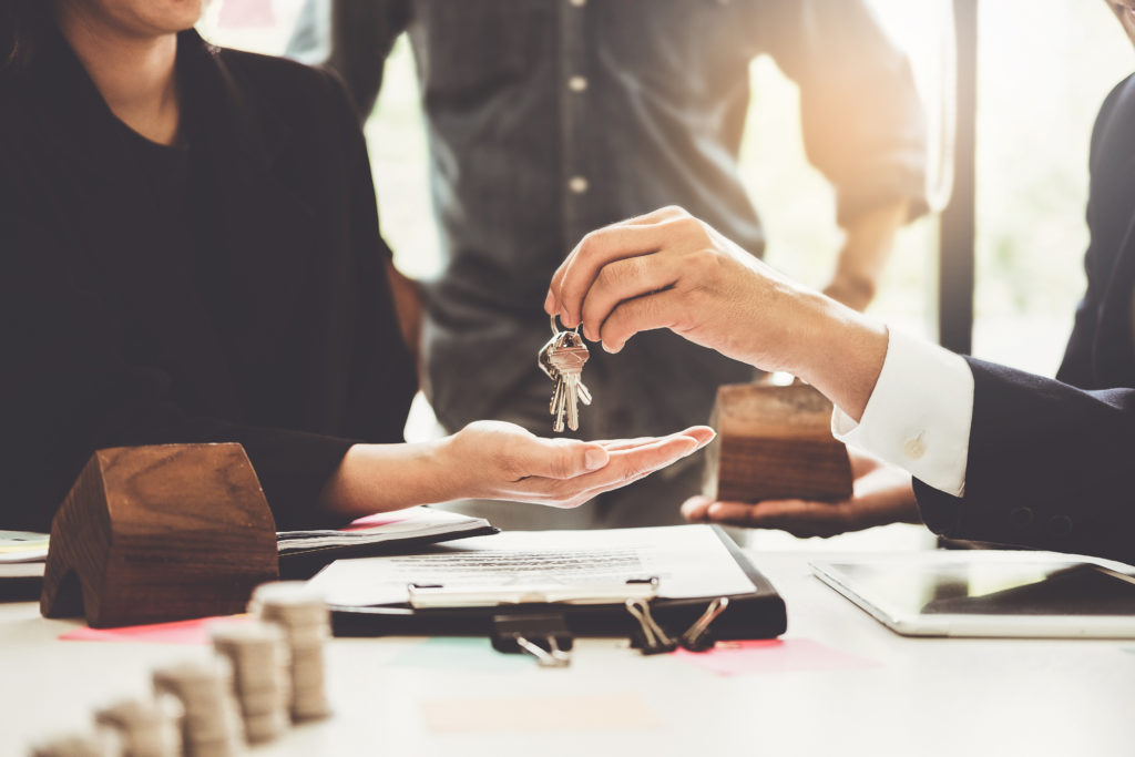 Agents are giving house keys of customer and holding dollar us bank at agency office. Agreement and real estate concept.