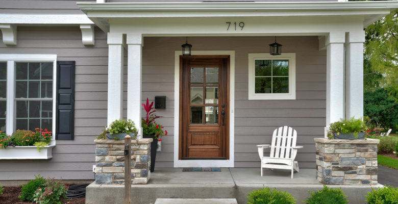 front porch of grey house with brown wooden door
