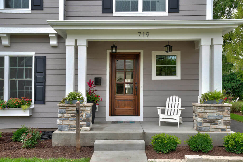 front porch of grey house with brown wooden door